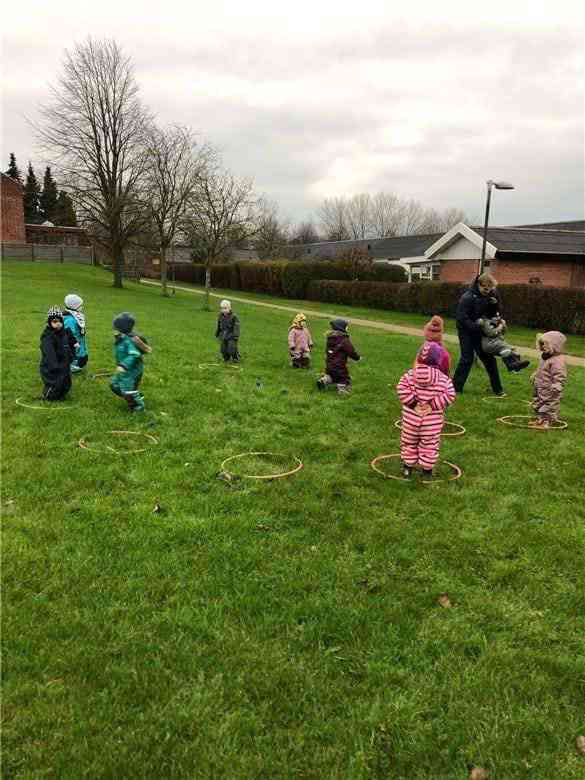 Børnene leger med hulahopringe i græsset